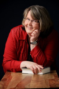 Porträtfoto von Nicole Gozdek, aufgestütztes Kinn und Buch in der anderen Hand